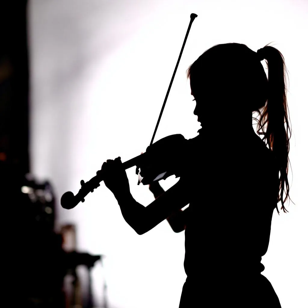 A silhouette of a girl playing a violin